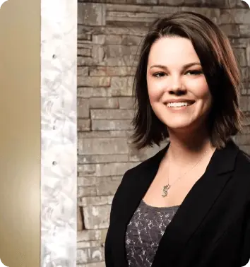 Person smiling in business attire against a stone wall background.